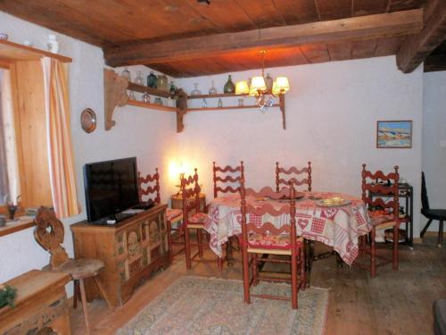 a dining room with a table and chairs and a television at Ancient Engadine Mill in Scuol