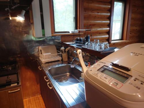 a kitchen with a sink and a stove at 恐竜博物館まで車10分バーベキュー機材無料貸出勝山ファミリーログハウス今日のおうち in Katsuyama