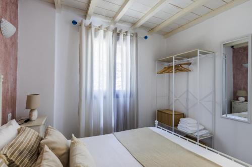 a white bedroom with a bed and a window at Villa Galazopetra in Skopelos Town