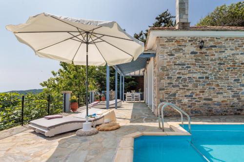 a pool with an umbrella next to a house at Villa Galazopetra in Skopelos Town