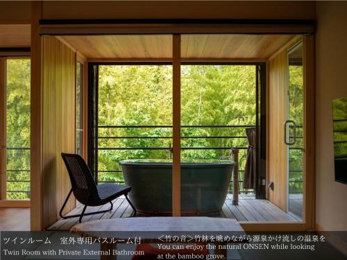 a bath tub in a room with a window at Tatsuta Ryokan in Izu