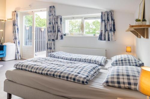 two beds in a room with windows at Bed & Breakfast de Lindevallei in Oldeberkoop