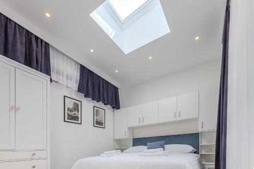 a white bedroom with two beds and a skylight at Fülöp Panzió Apartments near Lake Balaton in Révfülöp
