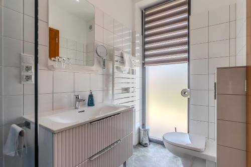 a white bathroom with a sink and a toilet at Fülöp Panzió Apartments near Lake Balaton in Révfülöp