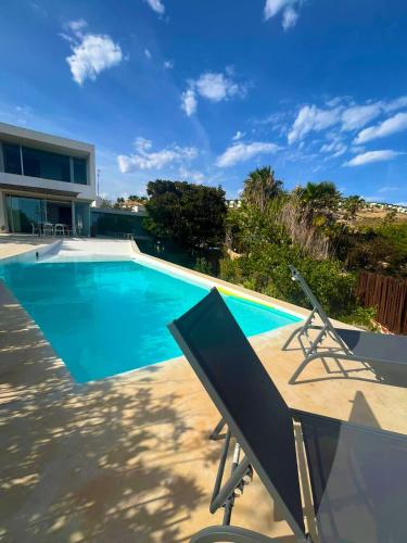 a swimming pool with two chairs next to a house at Villa Marta in Alicante