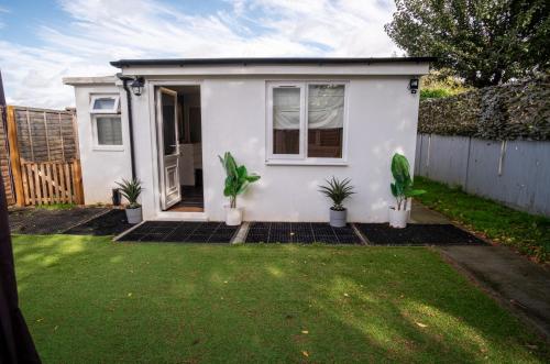 a small white house with plants in a yard at 1 Bed-Sleeps 4-Private Garden-Free Parking in St. Albans