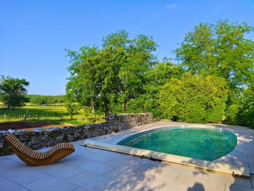 une piscine avec une chaise et un mur en pierre dans l'établissement Gite Valades - avec piscine et vue, à Saint-Antonin