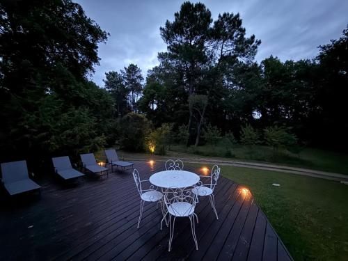 - une table et des chaises sur une terrasse la nuit dans l'établissement Le Peruguet - maison avec piscine et bois privé, à Margueron