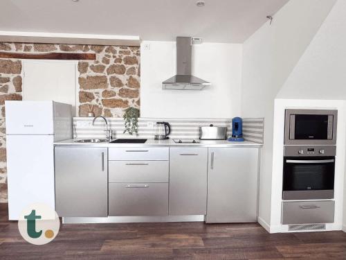 une cuisine blanche avec un évier et un micro-ondes dans l'établissement Tranquiloue - Maison 8 pers - Puy du Fou 15min, aux Herbiers