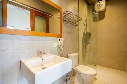 a bathroom with a sink and a toilet and a mirror at The Tanjung Bidadari Seminyak in Seminyak