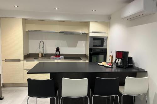 une cuisine avec un comptoir noir et des chaises blanches dans l'établissement Apartment for 4 with garden - near park, à Fréjus