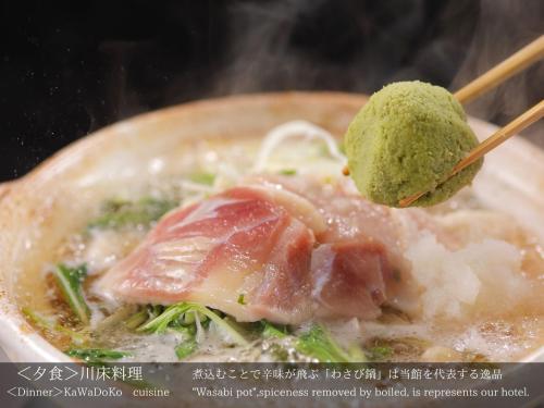 a bowl of food with meat and rice and a green sauce at Tatsuta Ryokan in Izu