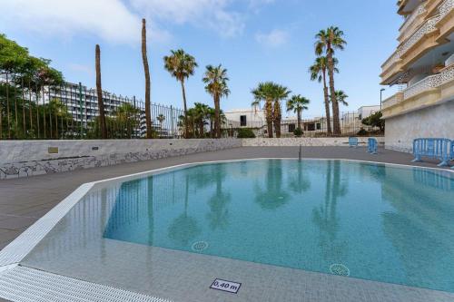 a swimming pool in a resort with palm trees at Cozy apartment with balcony, pool and Wifi in Playa de Las Americas in Playa de las Americas