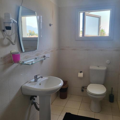 a bathroom with a sink and a toilet and a mirror at RIX Apartments in Kérynia