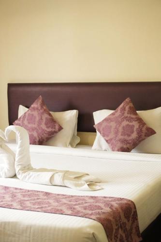 a bedroom with two beds with purple and white pillows at Hotel Kailas Residency Managed by Knight Hotels and Restaurants in Waluj Buzurg