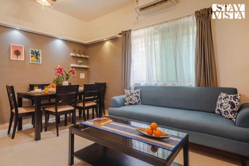 a living room with a blue couch and a table at Belas Palmeiras by VEO - Part of StayVista with Pool & Bonfire in Alibaug