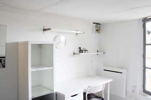 Cette chambre blanche dispose d'un bureau et d'étagères. dans l'établissement Beautiful studio for 2 in Versailles, à Versailles