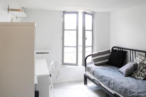 Cette chambre blanche dispose d'un banc avec des oreillers. dans l'établissement Beautiful studio for 2 in Versailles, à Versailles
