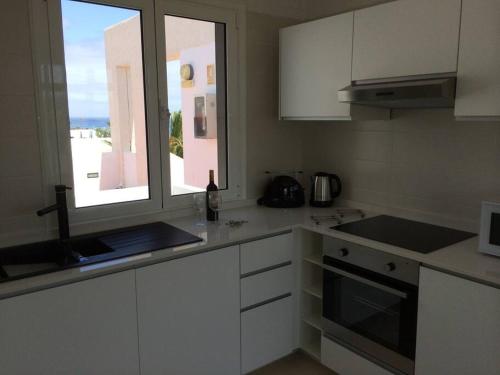 a kitchen with white cabinets and a window at B17 Caleton blanco in Tías