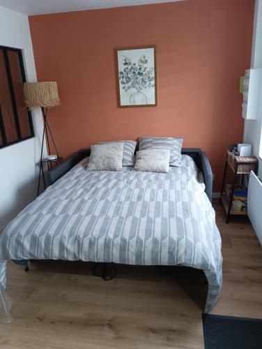 Ce lit se trouve dans une chambre dotée d'un mur orange. dans l'établissement Appartement cosy à Chamagne, à Chamagne