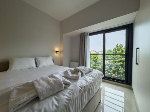 a bedroom with a white bed with a large window at VILLA 8 By ProLiving Hospitality in Thessaloniki