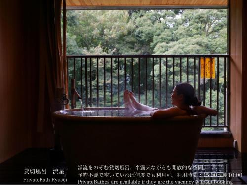 a woman sitting in a bath tub in a window at Tatsuta Ryokan in Izu