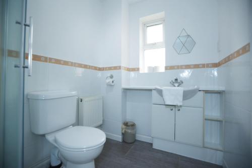 a white bathroom with a toilet and a sink at Milestone House By N And N Stays, Contractor Friendly, 6 Bed house, Sleeps 10, Private Parking, WIFI in Cardiff