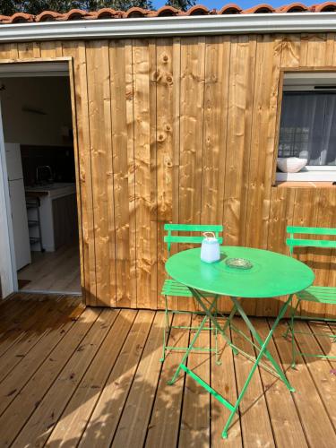a green table and two chairs on a wooden deck at Cocon cosy entre terre & mer in Le Fenouiller