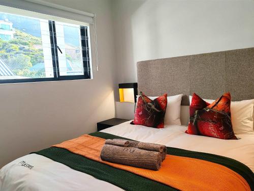 Un dormitorio con una cama con almohadas rojas y una ventana. en Wavescape Chic Seaside Stay, en Muizenberg
