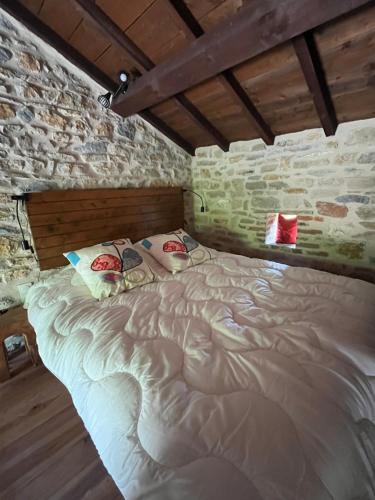 a large bed in a room with a brick wall at La ferme des Soudanières in Ceyzériat