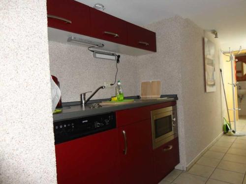 a red kitchen with a sink and a microwave at 2 Einbettzimmer in Neubrandenburg