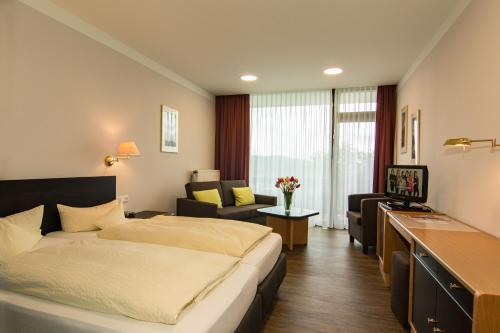 Habitación de hotel con cama y sofá en Garni Hotel & Ferienwohnungen Seeschlößchen en Waldeck