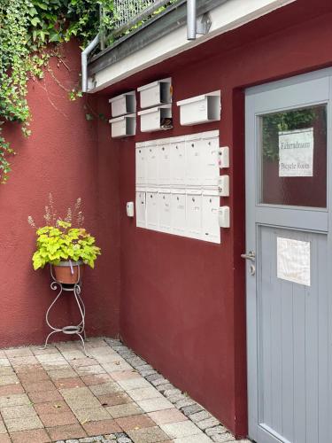 a red building with a door and a potted plant at FlamingoSuite 6 min zum See in Herrsching am Ammersee