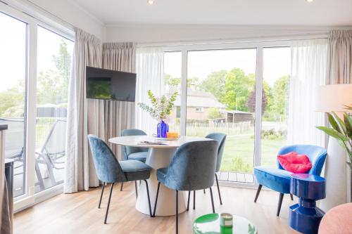 a dining room with blue chairs and a white table at Chalet Artistique in Oldeberkoop