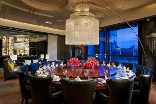 a dining room with a table and chairs and a chandelier at Sofitel Kunming in Kunming