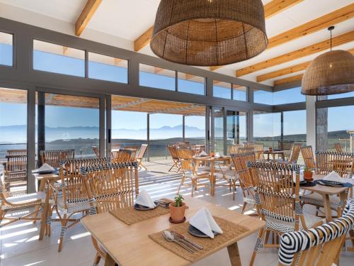 a restaurant with tables and chairs and windows at Goats Window Luxury Safari Lodge in Bonnievale