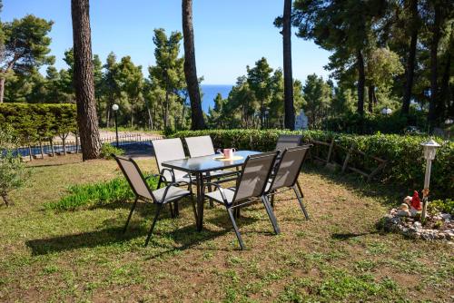 a table and chairs in a yard with trees at Sani Villa Elmira in Sani Beach