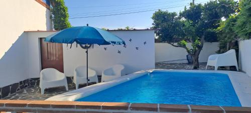 a swimming pool with an umbrella and chairs and a table with an umbrella at Casa dos Avós in Monsaraz