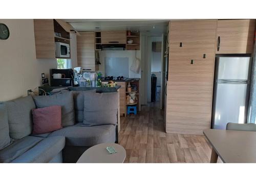 un salon avec un canapé et une cuisine dans l'établissement Mobil-home -Clim, TV, LV- Camping LE LAC DES RÊVES 4 étoiles - MH-A009, à Lattes