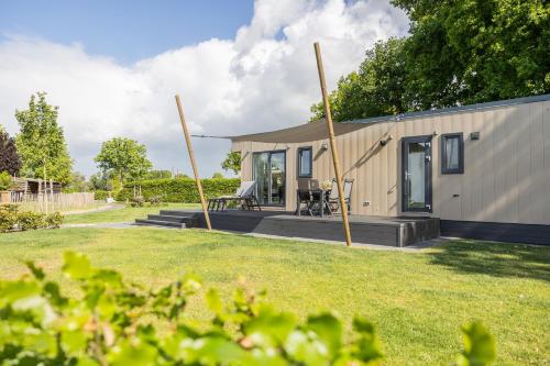 a tiny house with a patio and grass at Chalet Artistique in Oldeberkoop