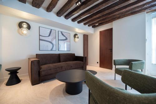 un salon avec un canapé, une table et des chaises dans l'établissement Charming Flat in Magnificient Place des Vosges, à Paris