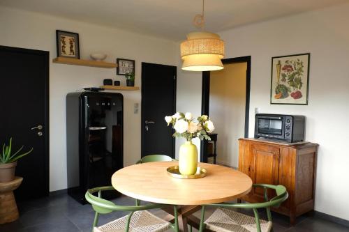 a dining room table with a vase of flowers on it at Au Petit Bercail - Le Fonteny - Gîte 2 personnes in Chiny
