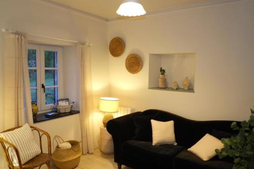 a living room with a black couch and a window at Au Petit Bercail - Le Fonteny - Gîte 2 personnes in Chiny