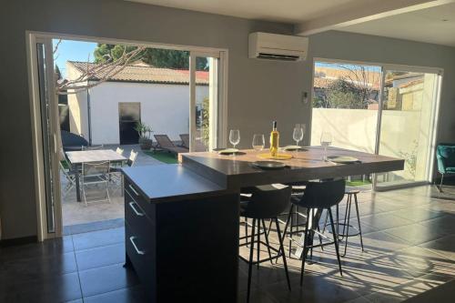 une cuisine avec un îlot et des tabourets de bar dans l'établissement Maison moderne de 100m2 avec jardin, à Vias