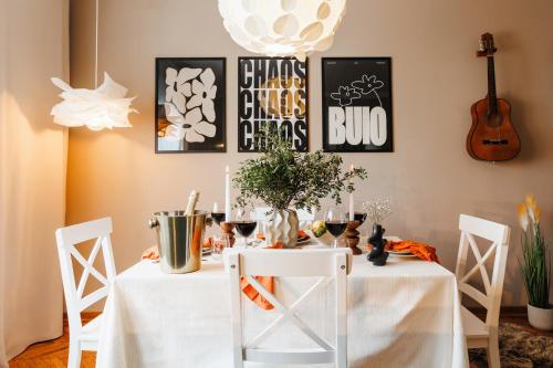 a dining room with a table with white tables and chairs at Harmonic Nest 3min to Republic Square Renovated in Belgrade