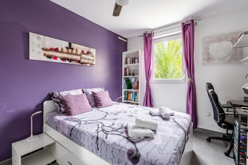 - une chambre violette avec un lit et un bureau dans l'établissement soleil d azur, à La Ciotat
