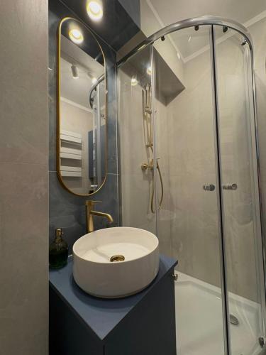 a bathroom with a white sink and a shower at Apartament Słowackiego Sopot in Sopot