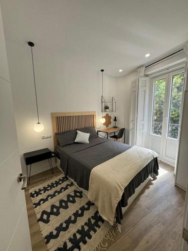 a bedroom with a large bed with a rug and a desk at Habitaciones plaza payor in Madrid