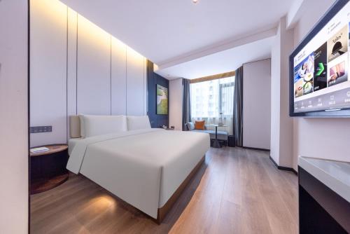 a bedroom with a white bed and a flat screen tv at Atour Hotel Chengdu Sichuan University North Kehua Road in Chengdu