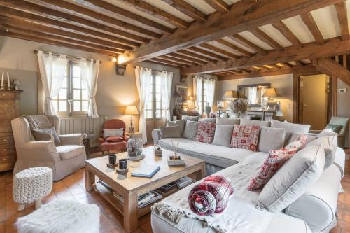 een woonkamer met witte meubels en houten plafonds bij La Moutinière, luxury cottage with pool in Manerbe